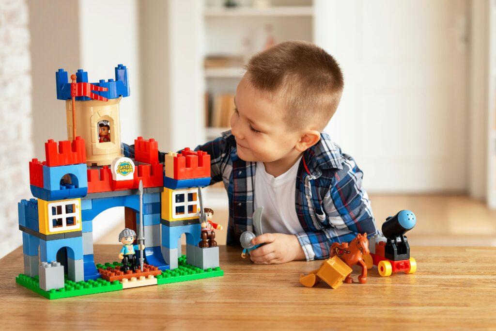 Young boy playing creatively with toy castle and figurines indoors, fostering imagination.